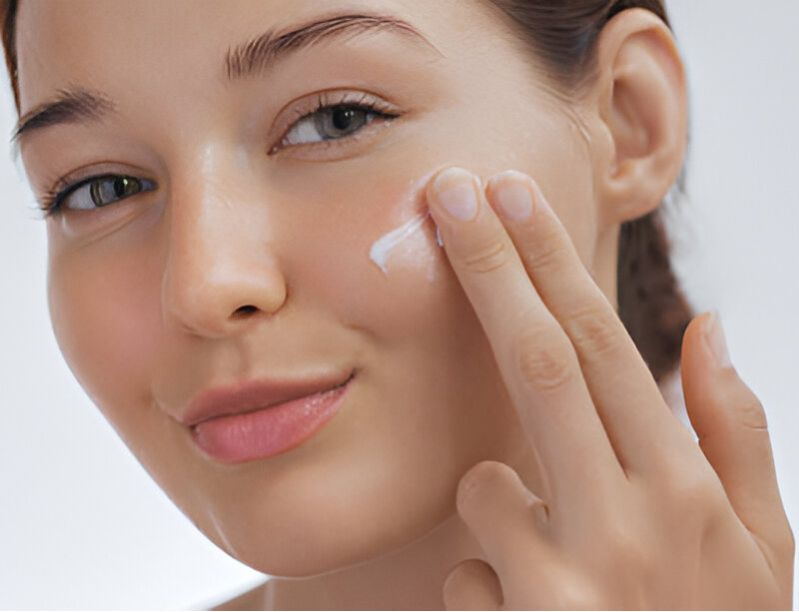 Woman applying product to her cheek, highlighting glowing, healthy skin, showing the moisturizing benefits of Pink Lady Bath and Body handmade soaps.