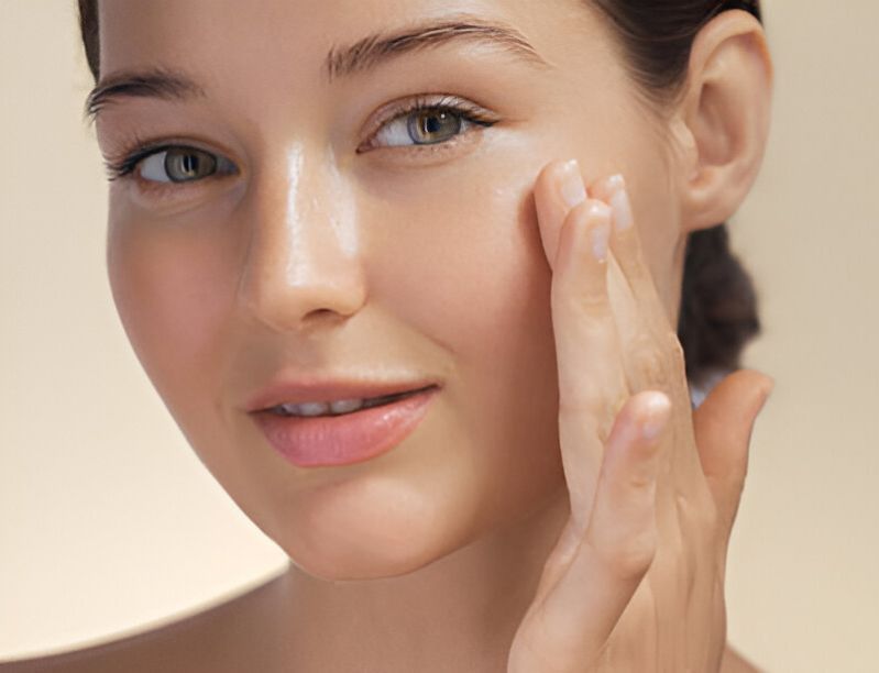 Woman applying product to her cheek, highlighting glowing, healthy skin, showing the moisturizing benefits of Pink Lady Bath and Body handmade soaps. 