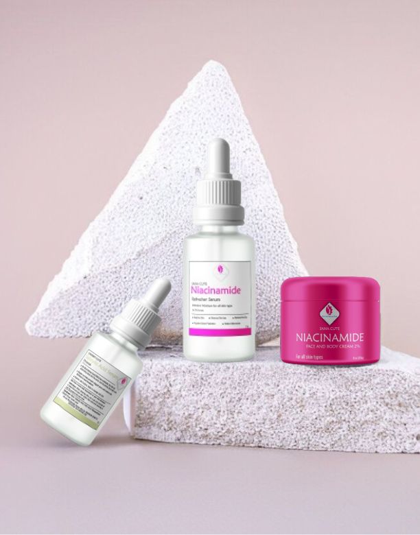 Pink Lady Bath and Body Niacinamide skincare kit, featuring the face and body cream in a pink jar and two serum bottles, displayed on a textured white prop.